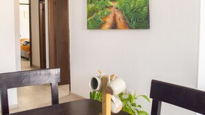 Un comedor con una mesa de madera oscura, sillas y un cuadro de un sendero en el bosque.