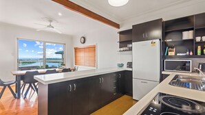 Une cuisine moderne avec vue sur l’extérieur, un coin repas avec une table et des chaises, et une cuisinière intégrée.