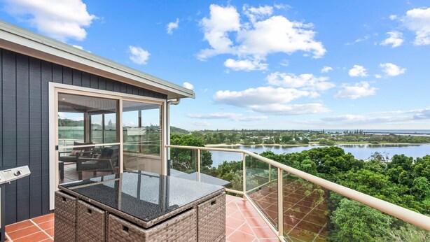 Un balcon doté d’une paroi vitrée donnant sur un lac et une végétation luxuriante.