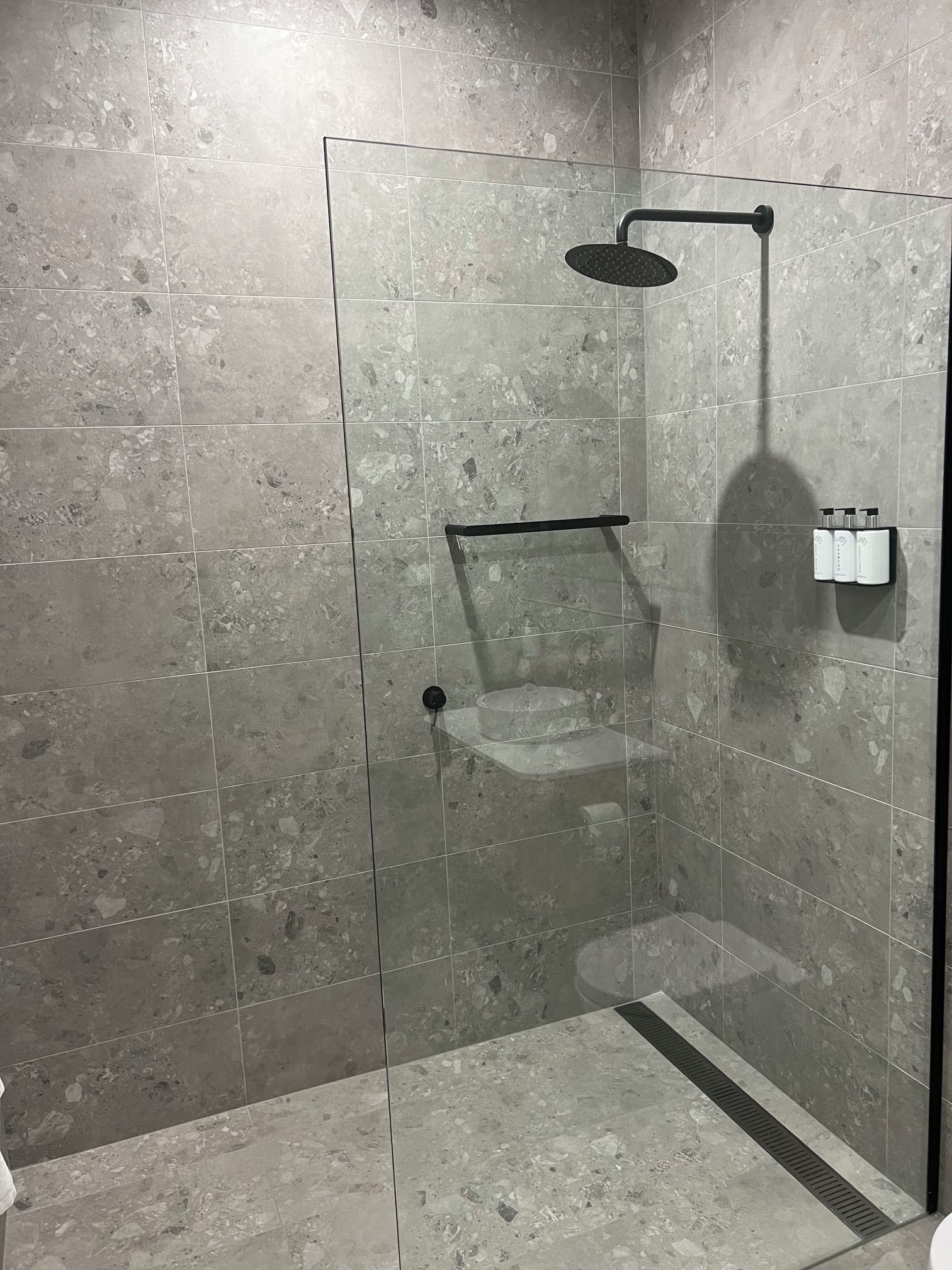Douchecabine met glazen wanden, handdouche, glazen deur en handdoekrek.