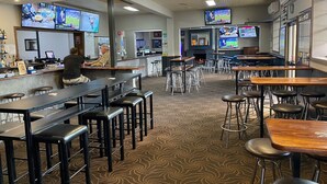 A bar area with multiple screens displaying sports events, bar stools, and a counter with a bartender. - Australian Hotel Young (Young)