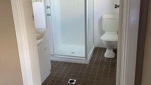 A bathroom with a shower enclosure, toilet, and sink. - Australian Hotel Young (Young)