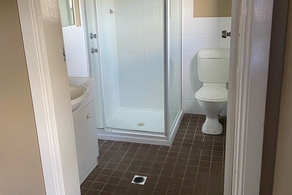 A bathroom with a shower enclosure, toilet, and sink.