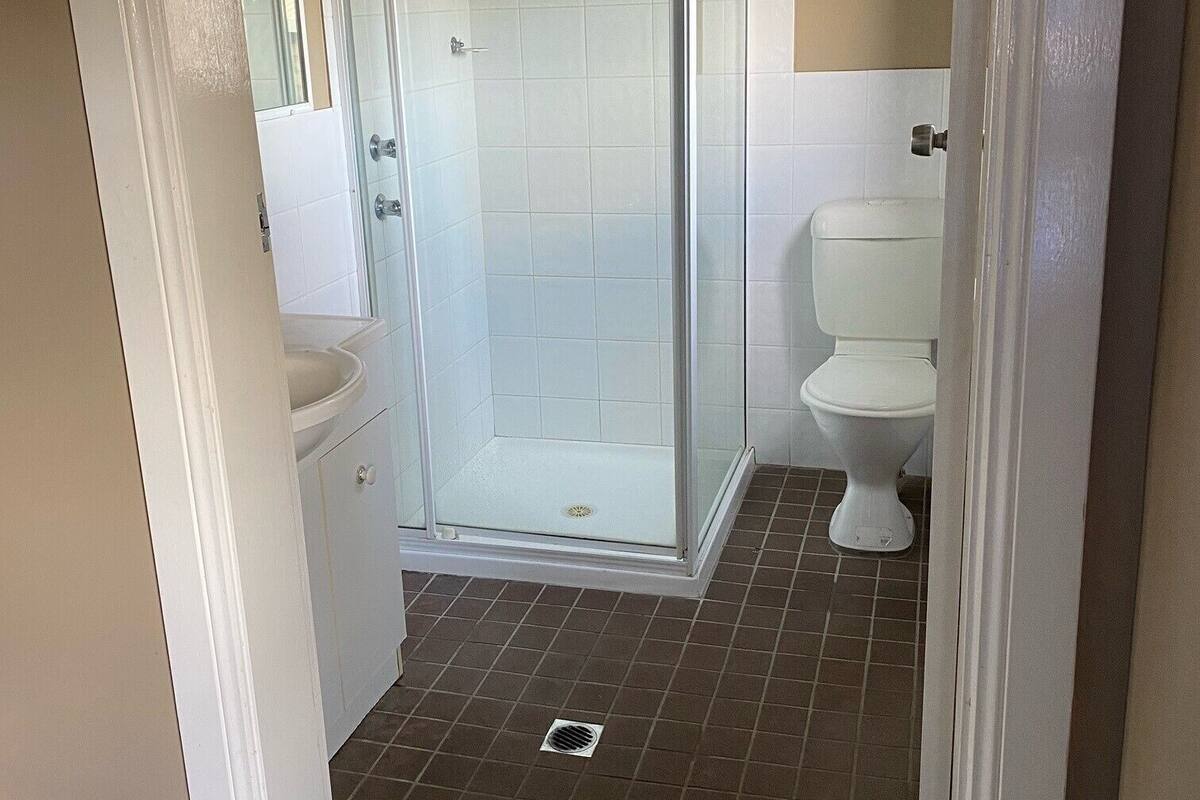 A bathroom with a shower enclosure, toilet, and sink.