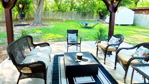 An outdoor patio with wicker furniture, a table, and a pergola with string lights. - Stylish design,king bed, fast WiFi. Safe, tranquil, minutes from central Dallas. (Dallas)