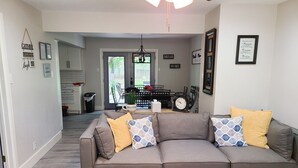 A living room with a grey sectional sofa, a coffee table, and a rug. There is a door leading to a dining area with a table and chairs. - Stylish design,king bed, fast WiFi. Safe, tranquil, minutes from central Dallas. (Dallas)