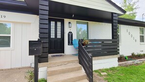 A house with a black front door, a welcome sign, and a mailbox. - Stylish design,king bed, fast WiFi. Safe, tranquil, minutes from central Dallas. (Dallas)