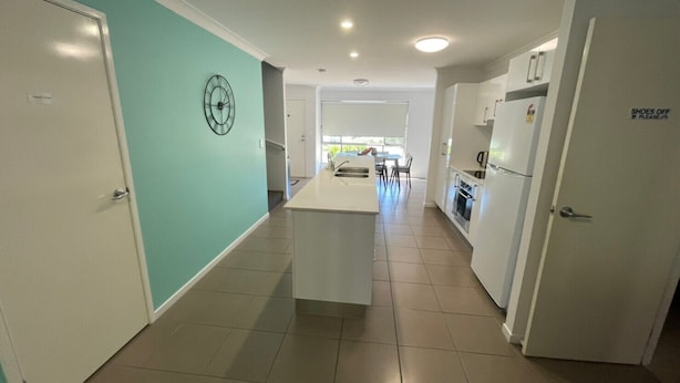 A modern kitchen with white cabinets, a central island, and a dining area with a table and chairs.