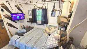 Une pièce comprenant un lit, un téléviseur, ainsi que divers outils et équipements fixés aux murs.
