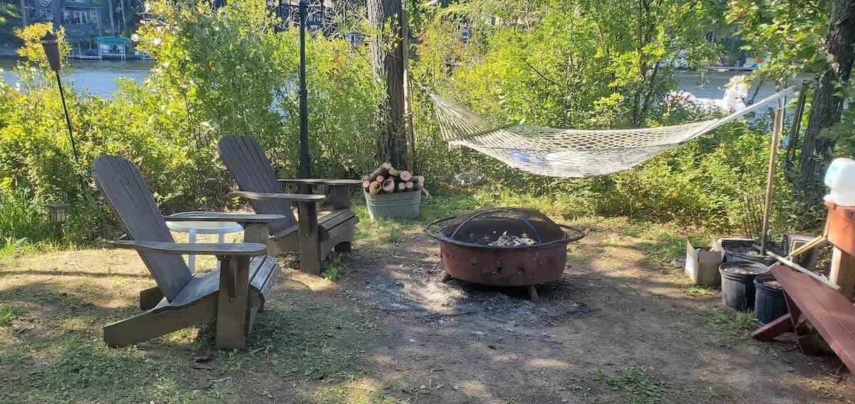 Un espace extérieur aménagé avec des chaises Adirondack, un foyer et un hamac.