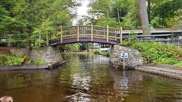 Un pont en bois enjambant une étendue d’eau paisible, entouré d’une végétation luxuriante et de murs de pierre.