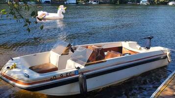 A small motorboat docked at a pier with a wakeboard in the background.