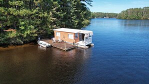 Une cabane sur pilotis au bord d’un lac, avec un quai et un petit bateau.