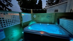 A hot tub in a wooden outdoor area with string lights. - Downtown Lakeside in Muskegon-by local businesses,10 min to beach, Htub seasonal (Muskegon)