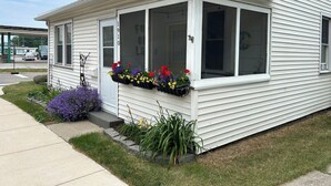 A white house with a covered porch, a front door, and a window with a flower box. - Downtown Lakeside in Muskegon-by local businesses,10 min to beach, Htub seasonal (Muskegon)