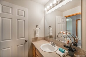 Bathroom features a large mirror, sink, and potted orchid.