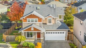 Une maison à deux étages avec un garage, un porche à l’avant et une pelouse bien entretenue.