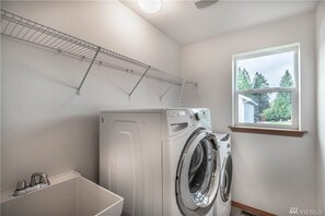 Convenient laundry facilities feature a front-loading washing machine and sink.