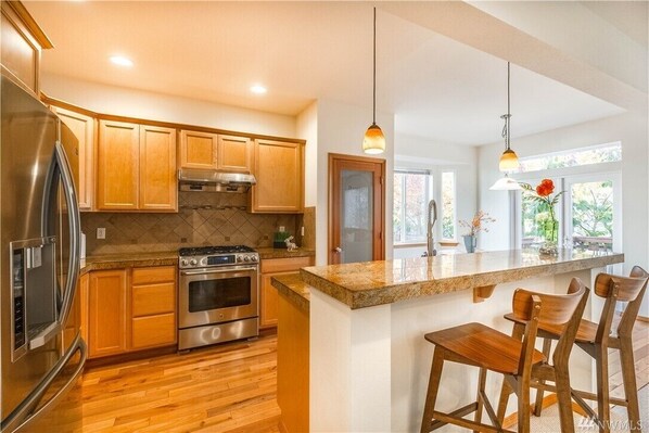 Enjoy cooking in this well-equipped kitchen with a central island, bar stools, and stainless steel appliances.