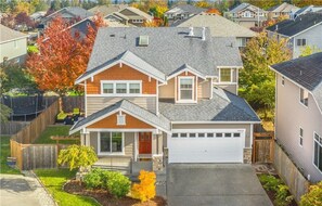 Une maison à deux étages avec un garage, un porche à l’avant et une pelouse bien entretenue.