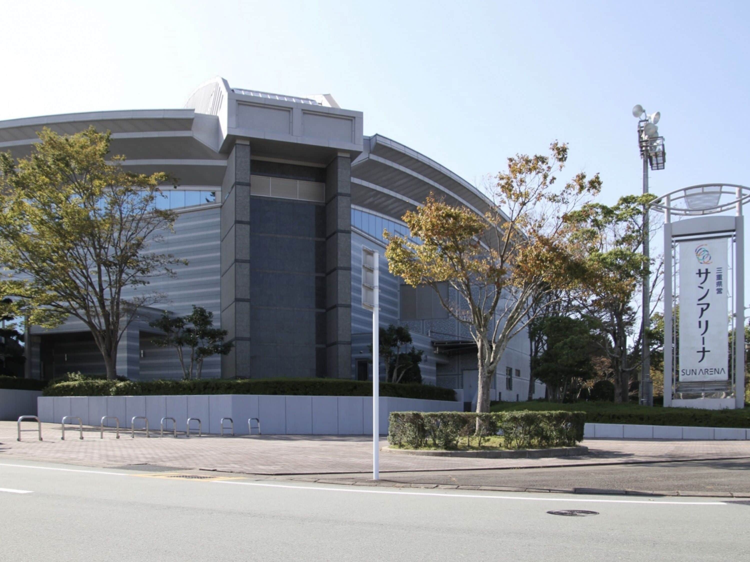 A modern building with a curved facade, a sign with Japanese characters, and a street in front.