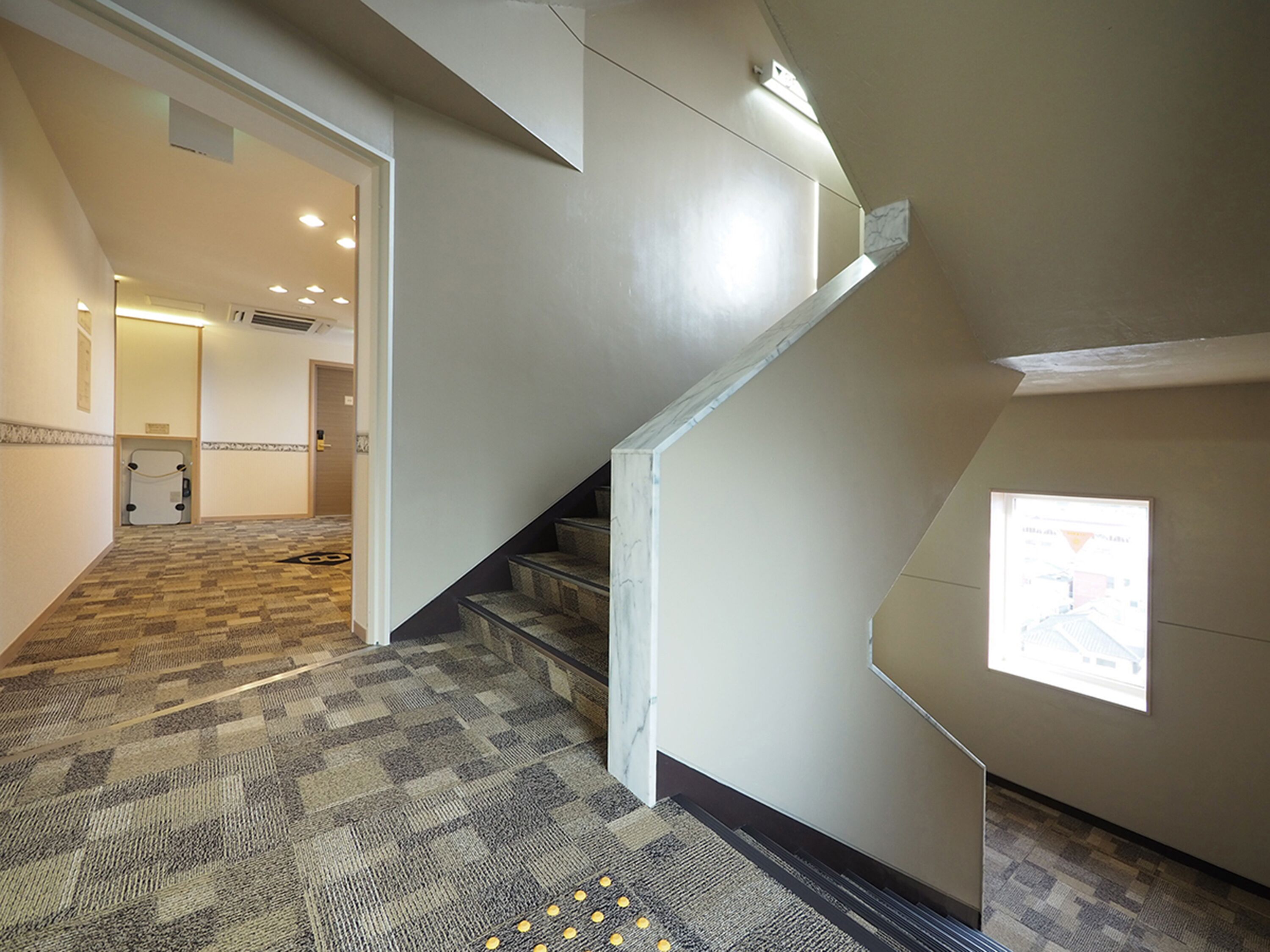A carpeted hallway with a staircase leading to a room.