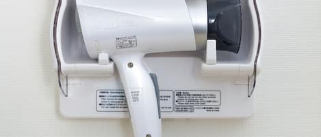 A hair dryer mounted on a wall with a power cord.