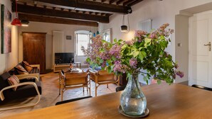 A living room with a wooden table, a sofa, a TV, and a vase with flowers.