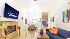 Uma sala de estar moderna com televisão de tela plana, lareira, sofá e espaço para refeições.