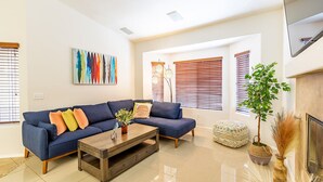 Uma sala de estar moderna com um sofá azul, uma mesa de centro e uma lareira.