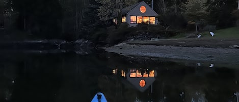 A kayak on calm water with a house in the background.