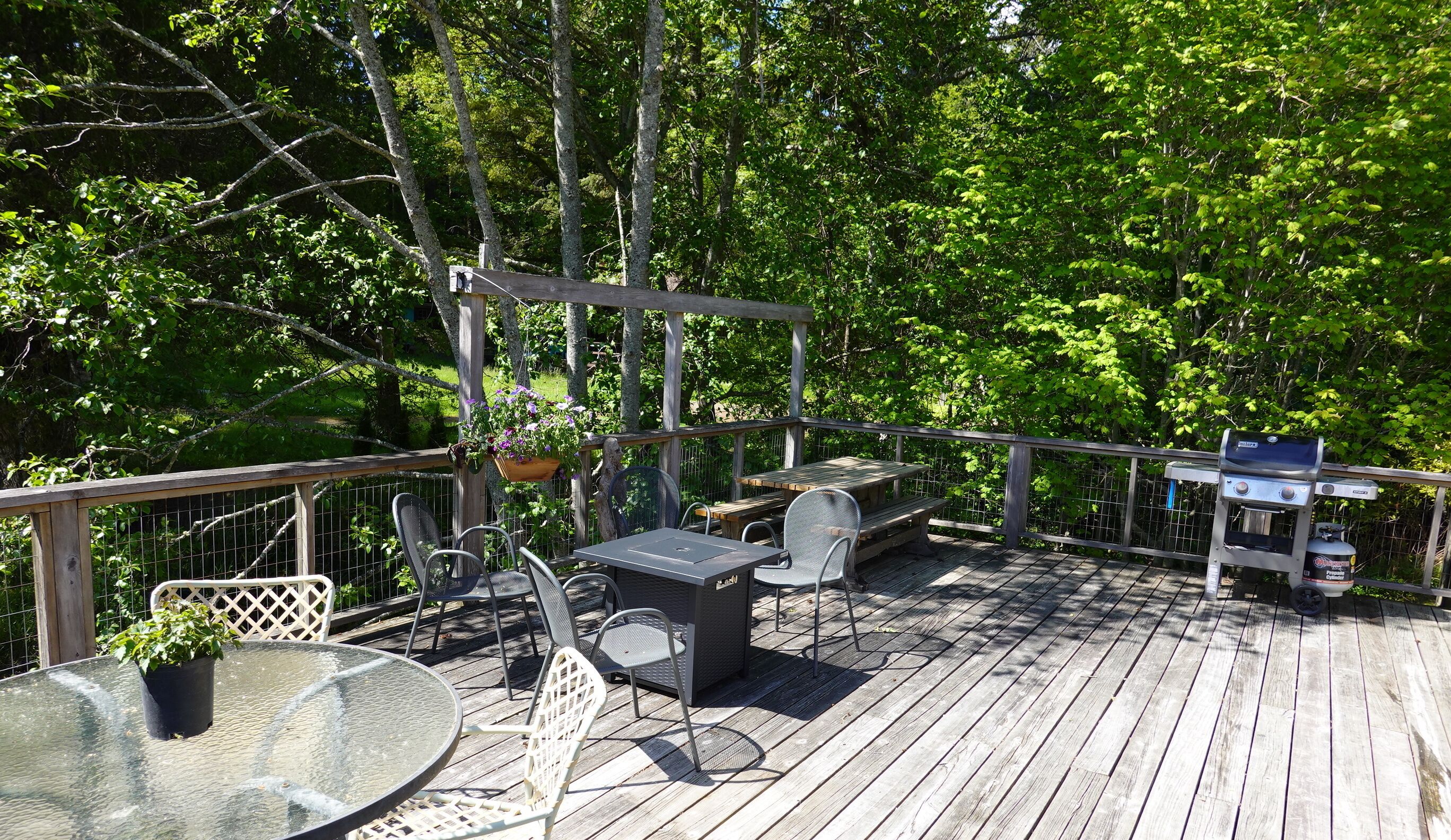 Ett trädäck med utemöbler, inklusive ett bord och stolar, samt en grill.