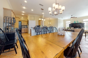 A spacious dining area with a large wooden table and black chairs, a kitchen with wooden cabinets, and a fireplace.