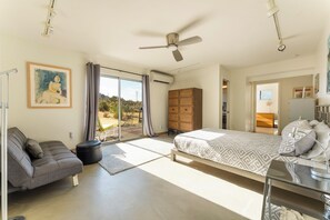Un dormitorio con cama, sofá, armario y un cuadro en la pared.