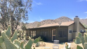 Une maison dotée d’un patio, entourée de cactus et de plantes du désert.