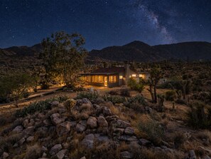 A house with a large open patio, surrounded by desert vegetation and mountains under a starry night sky. - Joshua Tree Dream Weaver a chic home on 5 private acres (Joshua Tree)