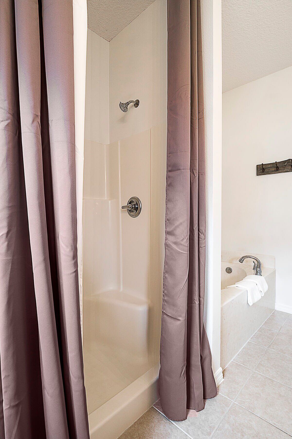A bathroom with a shower, a bathtub, and a towel rack.