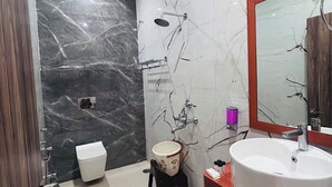 Un baño con pared de mármol, un lavamanos, un inodoro y una ducha.