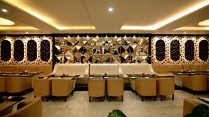 Un restaurante moderno con una zona de estar central, varias mesas y un diseño de pared con motivos.