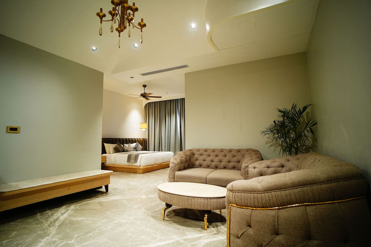 A modern bedroom with a large bed, a sofa, and a bench.
