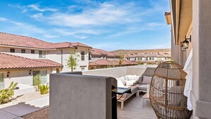 A balcony with a sofa, a wicker chair, and a view of neighboring buildings. - Magnolia Lane by RedAwning (Washington)