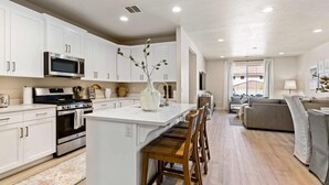 A modern kitchen with white cabinets, stainless steel appliances, and a central island with bar stools. - Magnolia Lane by RedAwning (Washington)