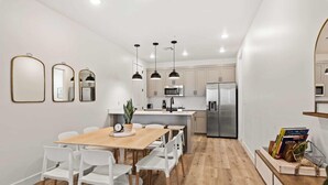 A modern kitchen with white cabinets, a wooden dining table, and three pendant lights. - Chillin Out Maxin #96 by RedAwning (St. George)