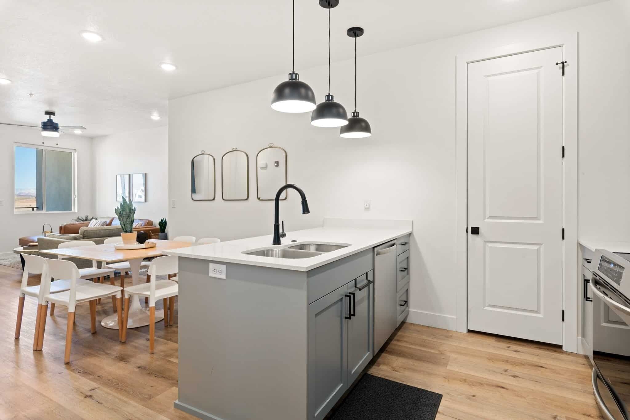 A modern kitchen with a central island, white cabinetry, and pendant lighting.