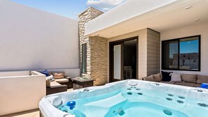 Une terrasse sur le toit avec un jacuzzi, des sièges d ’extérieur et un mur en pierre.