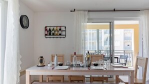 A dining area with a wooden table set for four, a wine rack on the wall, and a view of a balcony with white railings. - Les jardins de l'oyat by Interhome (Mimizan)