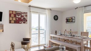 A modern living room with a sofa, a dining table, and a kitchen area. - Les jardins de l'oyat by Interhome (Mimizan)