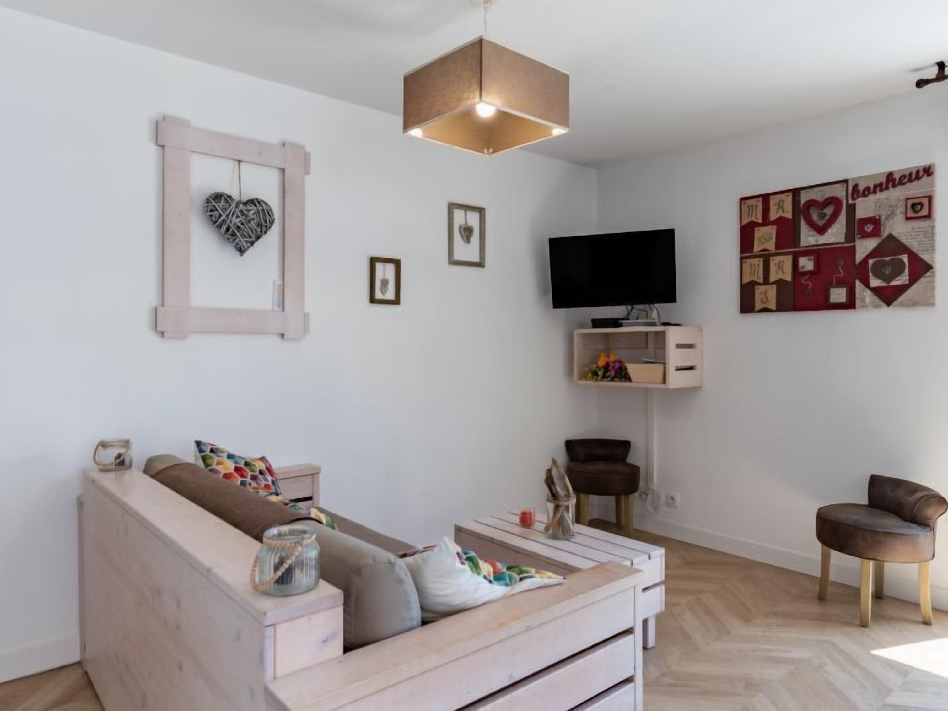 Un salon moderne comprenant un canapé, une table basse, un téléviseur et une étagère fixée au mur.