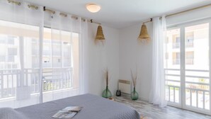 A bedroom with a bed, large windows, and a balcony. - Les jardins de l'oyat by Interhome (Mimizan)