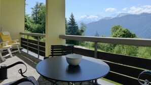 A balcony with a table and chairs, a bowl, and a mountain view. - Enzian 720 by Interhome (Beatenberg)
